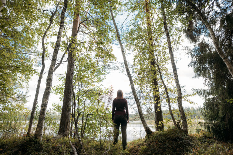 Nainen metsässä katsomassa järvelle/ Woman in the forest looking at a lake