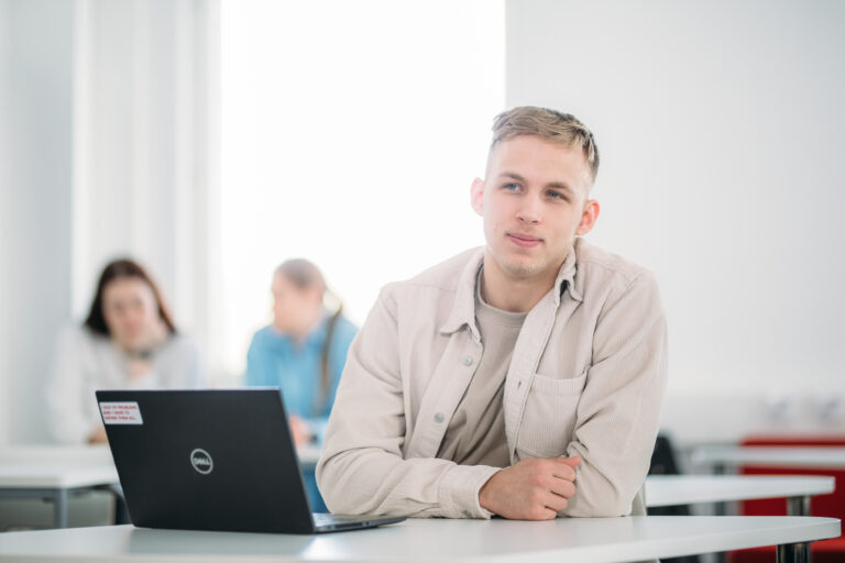 Opiskelija tietokoneella pöydän äärellä / A student at a desk with a computer.