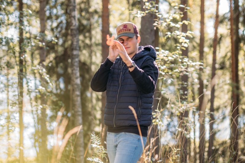 henkilö tähtää mittaustyökalulla metsässä / person aiming with a measuring tool in a forest