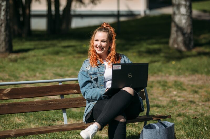 henkilö puistonpenkillä läppärin kanssa / person on a park bench with a laptop